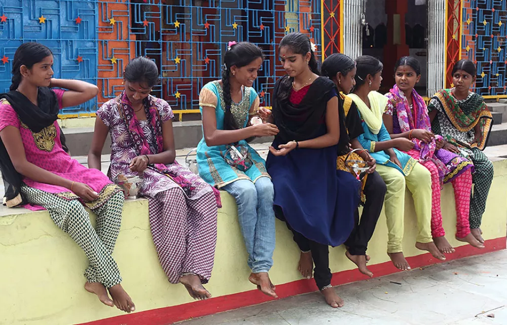 Girls in colourful outfits sitting on a wall